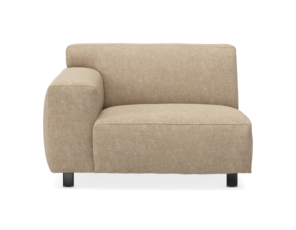 Beige modulsoffdel med vänster armstöd, låg rygg och svarta ben, sedd framifrån mot vit bakgrund.