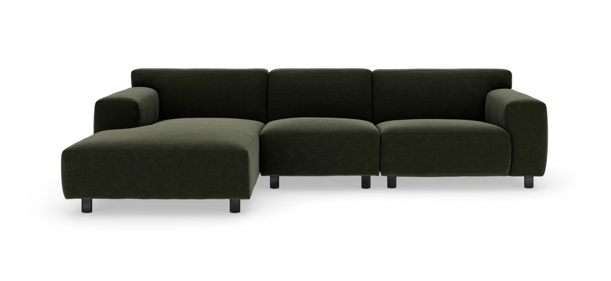 Mörkgrön modulsoffa med vänster divan, breda armstöd och metallben, frilagd på vit bakgrund.