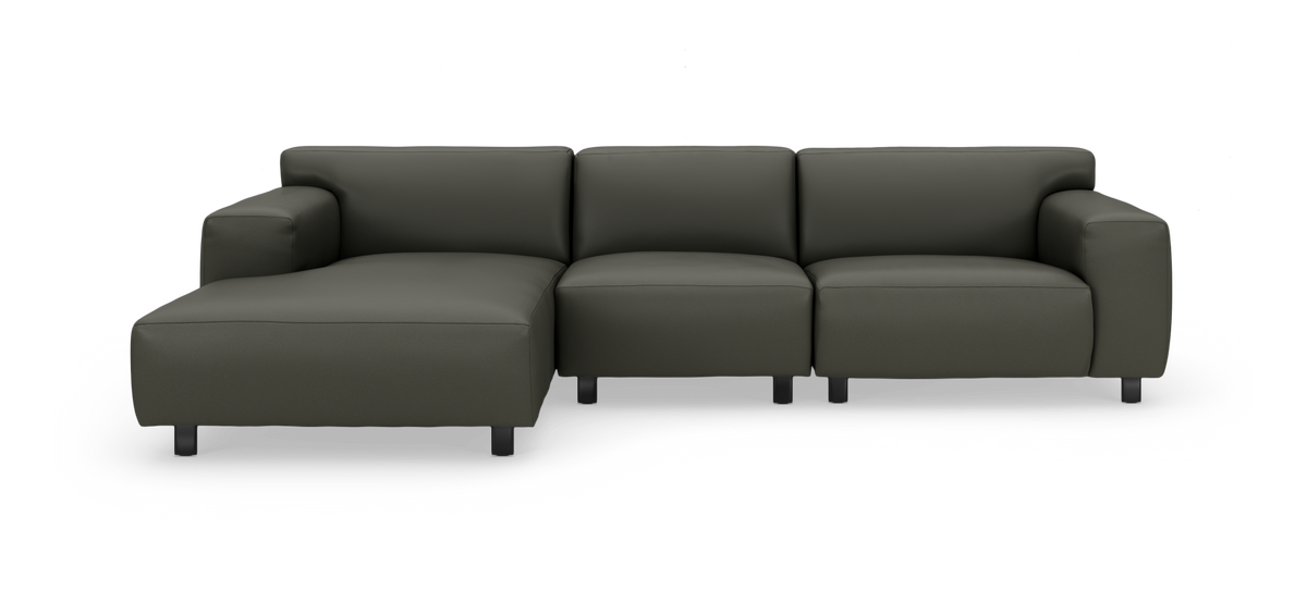 Modulär L‑soffa med vänster schäslong i mörk olivgrön/antracit, modern och minimalistisk, fristående mot vit bakgrund.