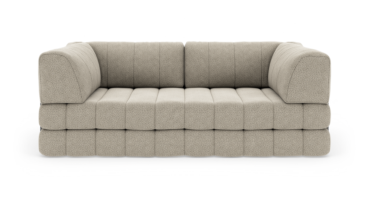 Beige modulsoffa med rundade armstöd i bouclé-liknande tyg, fotograferad framifrån mot vit bakgrund.