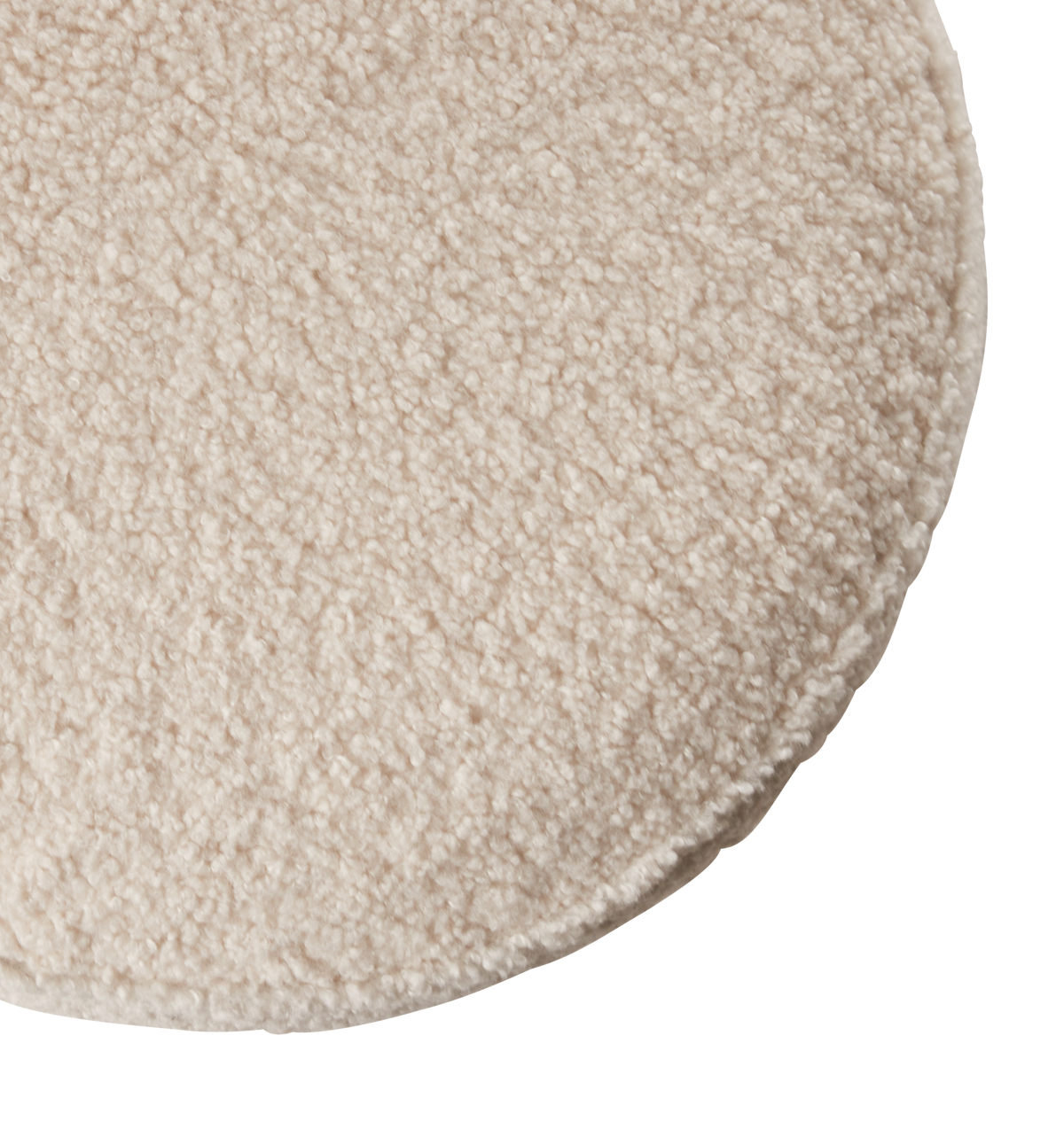 Närbild av ett runt beige texturerat ryamatta med mjuk bouclé-yta.