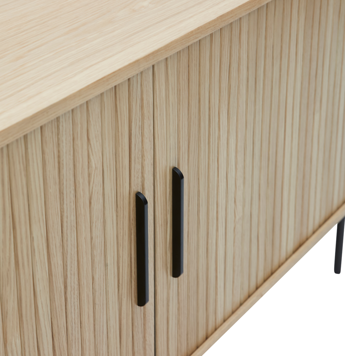 Närbild av en ljus ekfanerad sideboard med vertikala lameller och svarta metallhandtag.