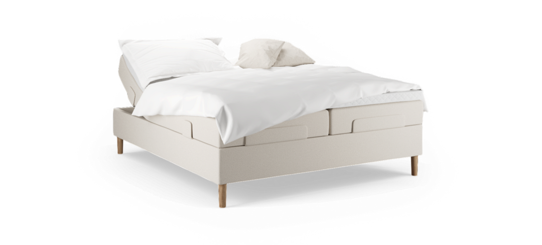Beige justerbar säng med vita sängkläder och två kuddar, träben, frilagd mot svart bakgrund.