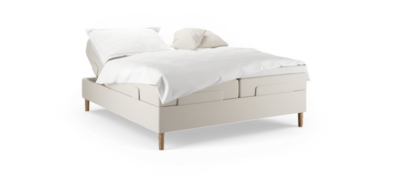 Beige justerbar säng med vita sängkläder och två kuddar, träben, frilagd mot svart bakgrund._ps