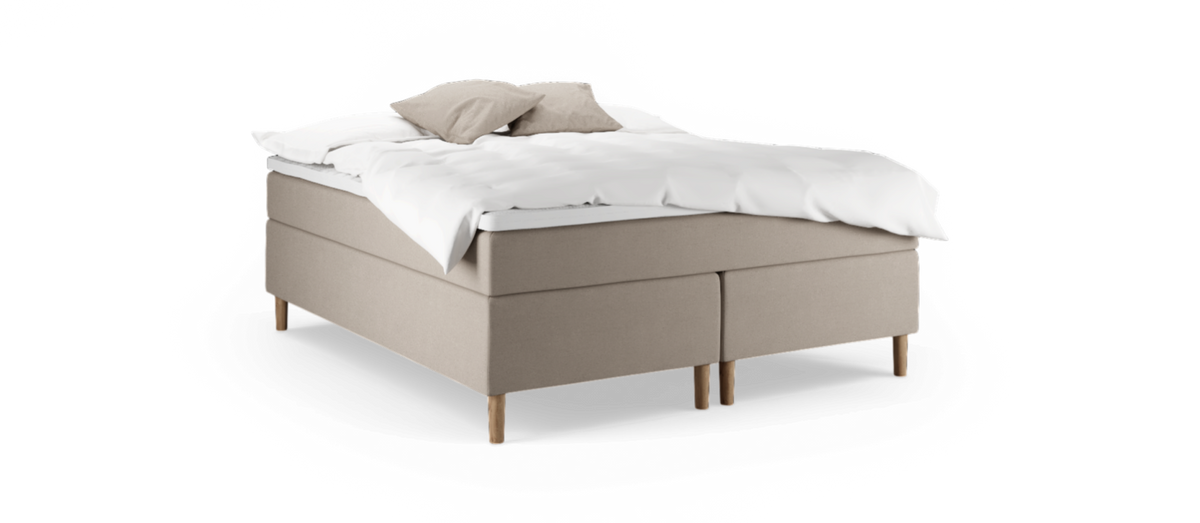Beige kontinentalsäng med träben, vit bäddmadrass och två beige kuddar.