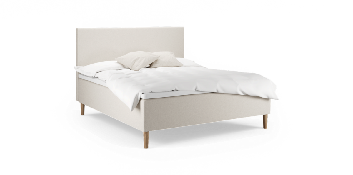 Beige stoppad säng med träben, vit bäddning och två neutrala kuddar, frilagd.
