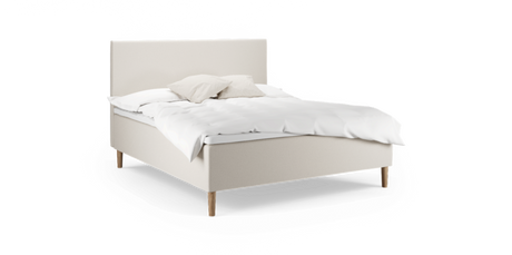 Beige stoppad säng med träben, vit bäddning och två neutrala kuddar, frilagd.
