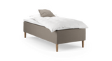Enkel enkeltsäng med beige klädd sängbas, vit kudde och täcke samt träben, frilagd på vit bakgrund._ps