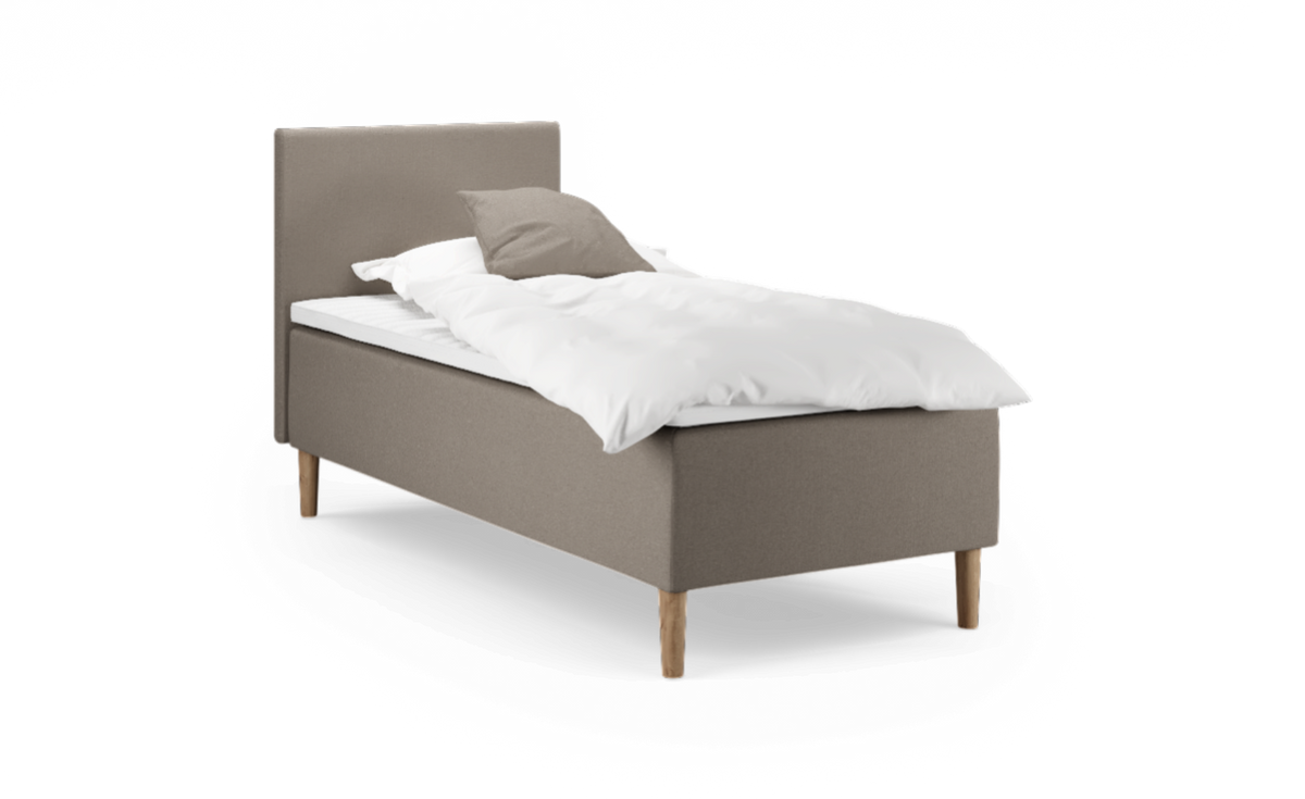 Beige stoppad enkelsäng med trärben, vitt täcke och taupefärgad kudde, frilagd mot vit bakgrund.