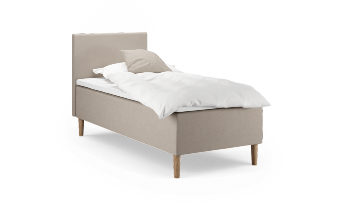 Enkeltsäng med beige klädsel, träben och vit bäddning.