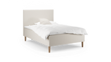 Beige stoppad enkelsäng med hög sänggavel, vit bäddtextil och träben._ps