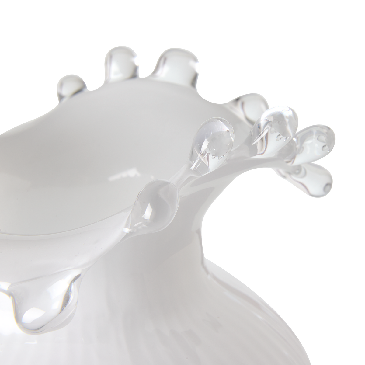 Närbild av en vit glasvas med klara droppformade detaljer längs kanten.