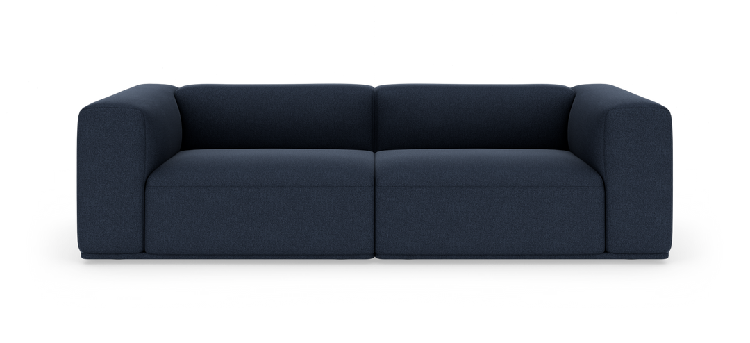 Mörkblå, modern modulsoffa med mjukt rundade armstöd, fotograferad rakt fram på vit studiobakgrund.