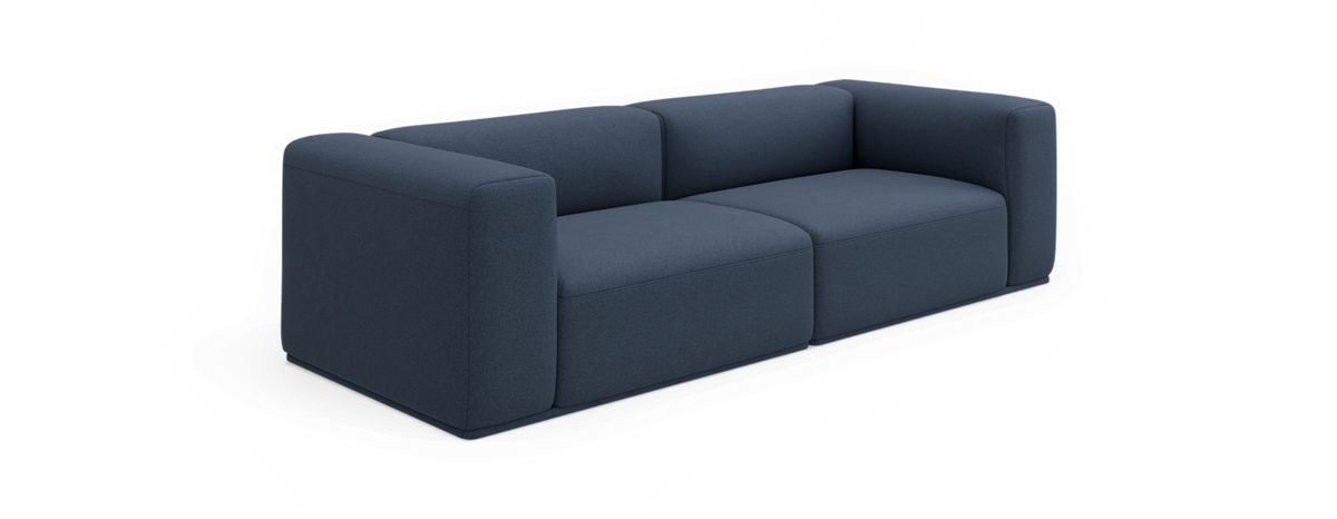 Mörkblå modern 2‑sits soffa med tjocka, rundade kubiska armstöd och låg profil, frilagd på svart bakgrund.